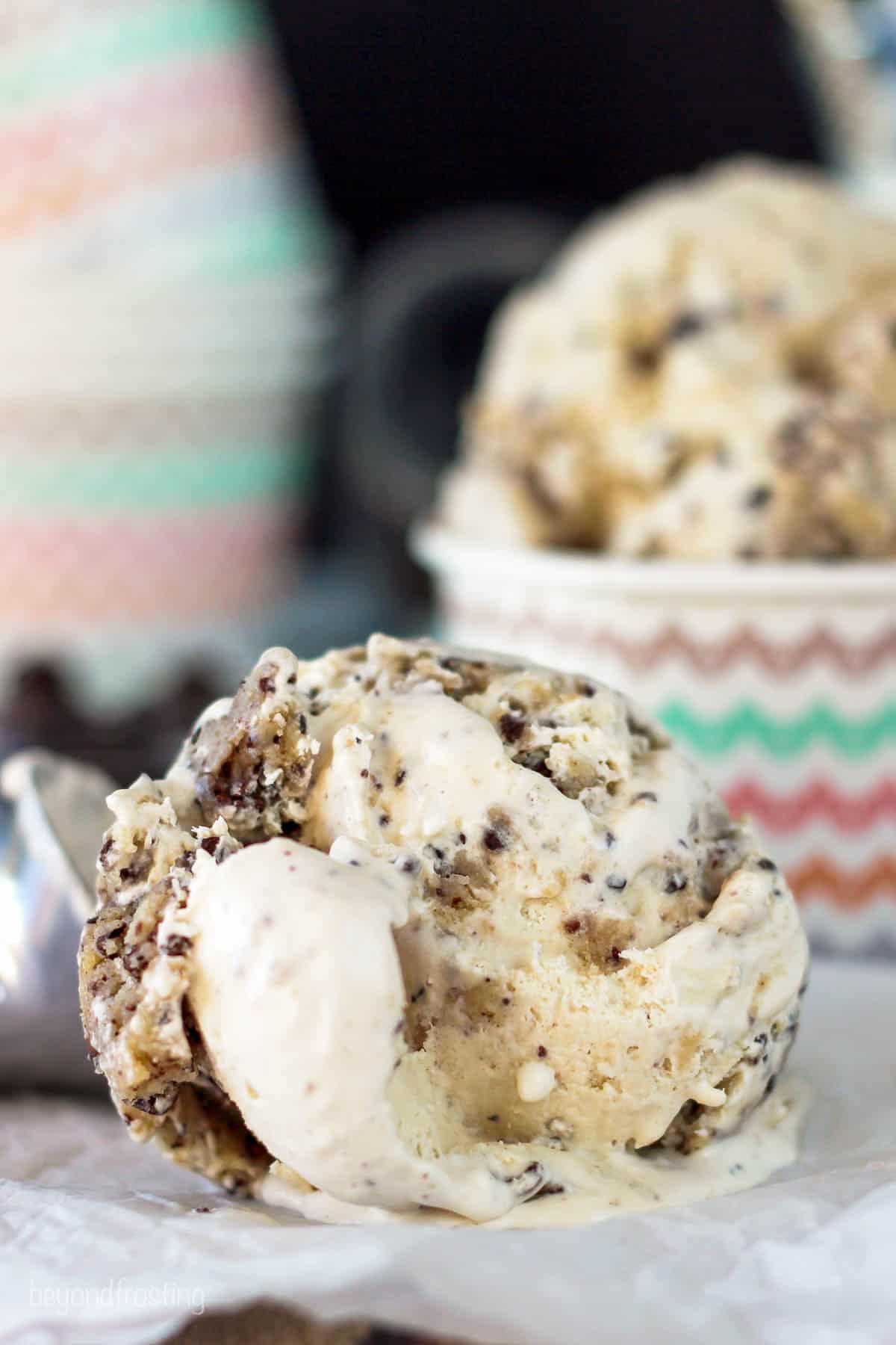 a scoop of espresso ice cream on a piece of parchment paper with a container of ice cream in the background