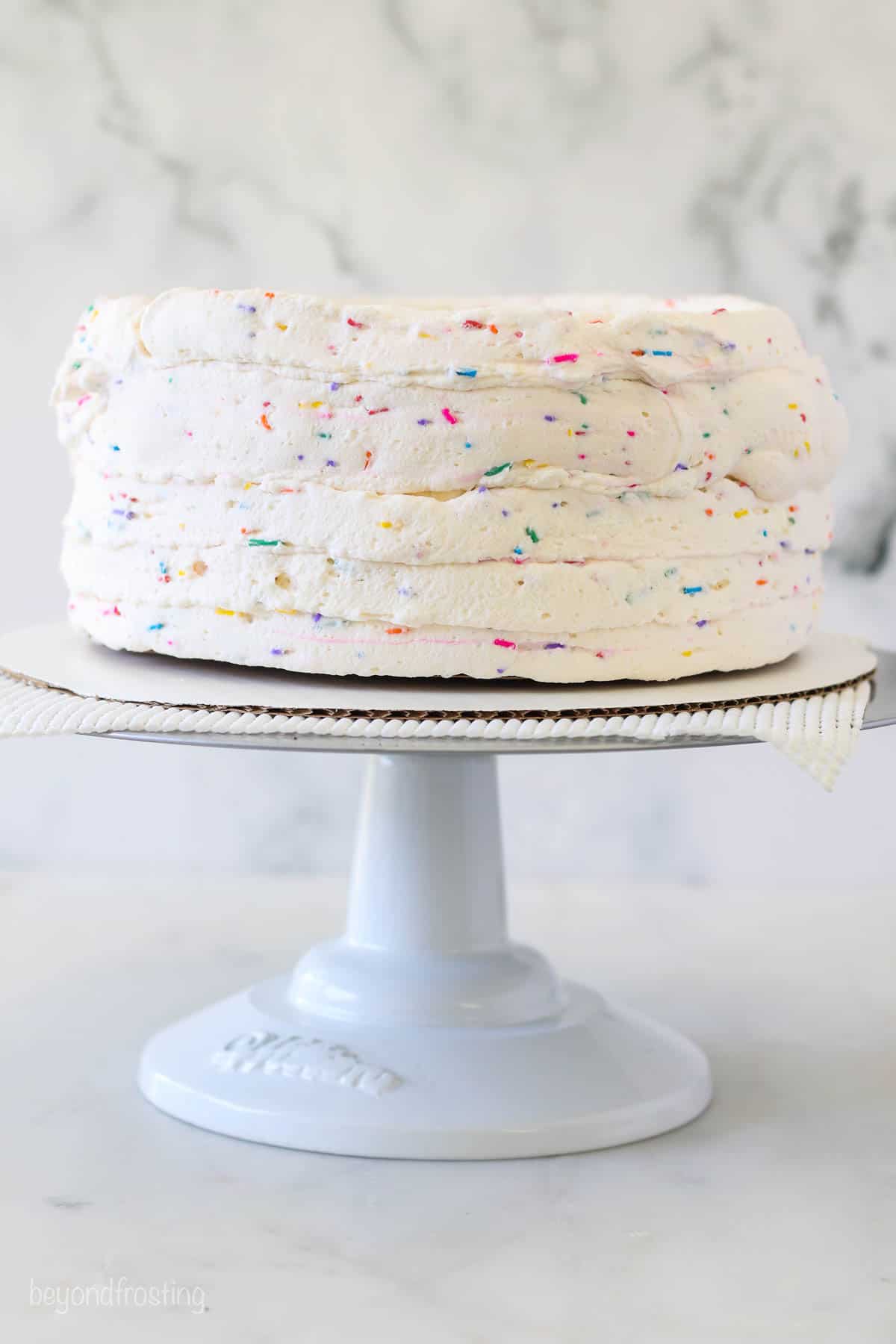 An ice cream cake on a cake board decorated with sprinkle whipped cream