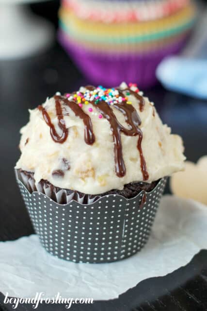 side view of a frosted chocolate cupcake drizzled with hot fudge sauce