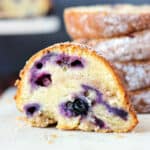 A slice of lemon blueberry bundt cake with more slices stacked in the background.