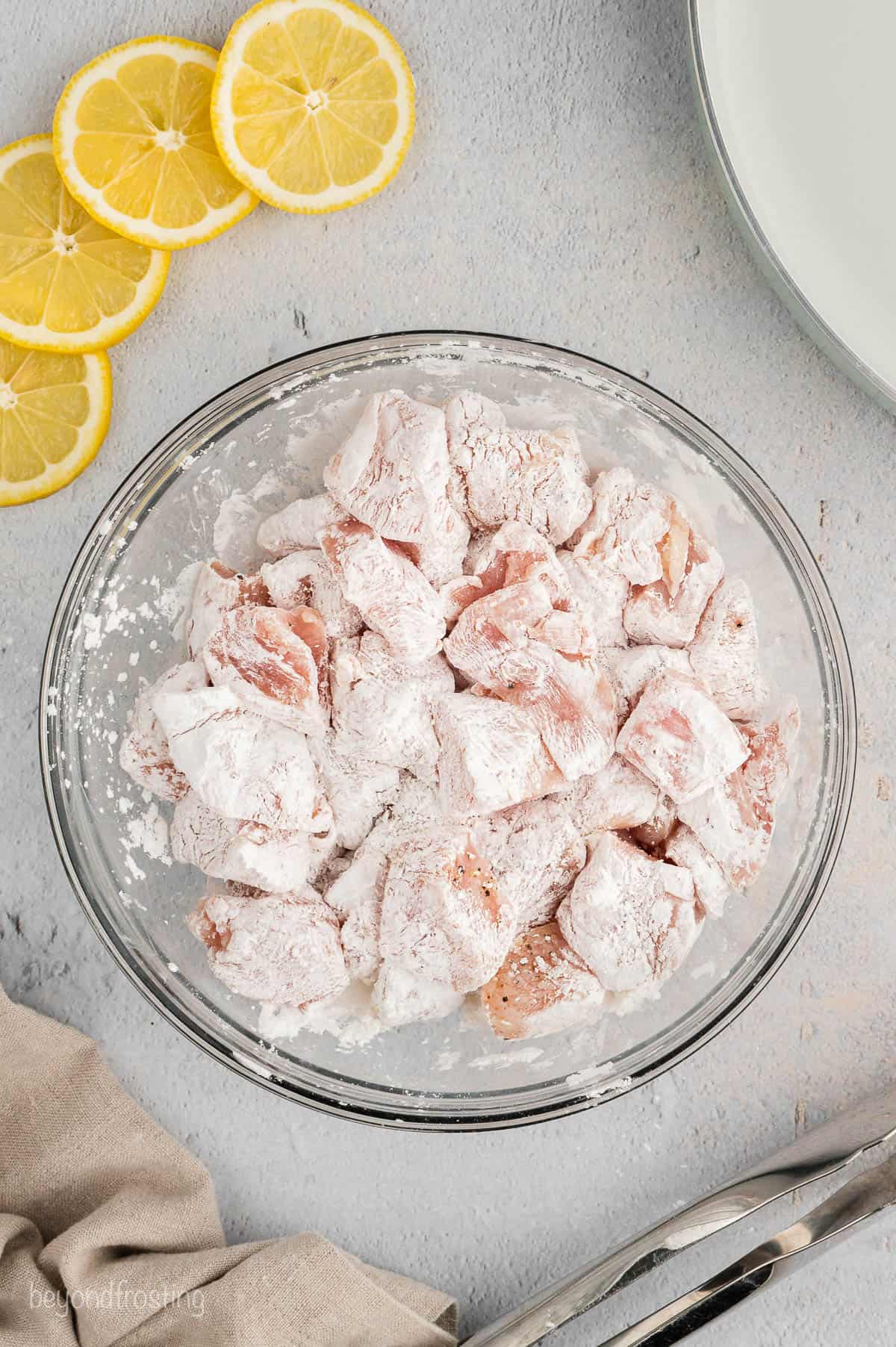 Diced chicken tossed with cornstarch in a glass bowl