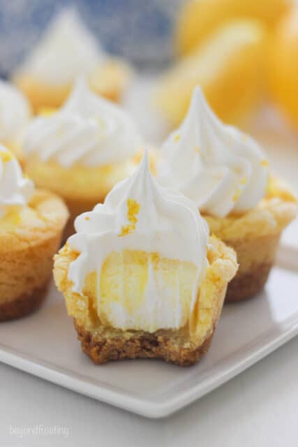 side view of a plate filled with lemon cookie cups with a bite taken out of the front one