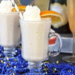 closeup of a mimosa milkshake garnished with whip and an orange slice