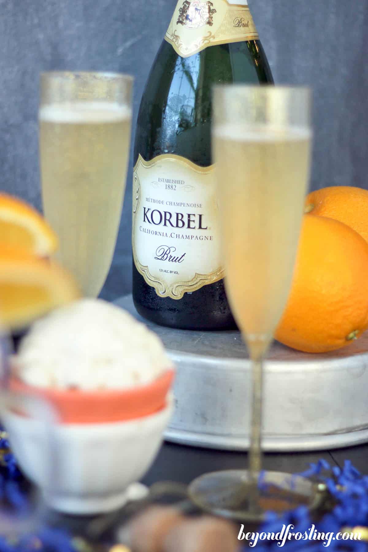 side view of two champagne glasses in front of a bottle