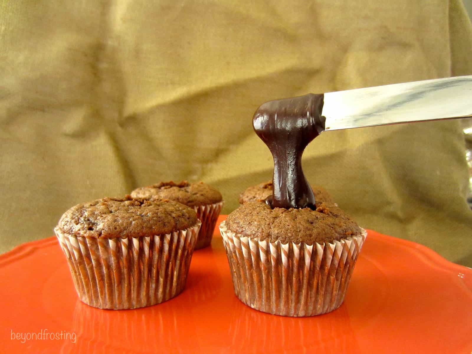 irish cream cupcakes being filled with chocolate sauce