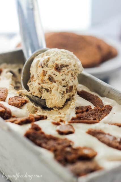 a scoop of ice cream being taken out of a tin of molasses cookie ice cream
