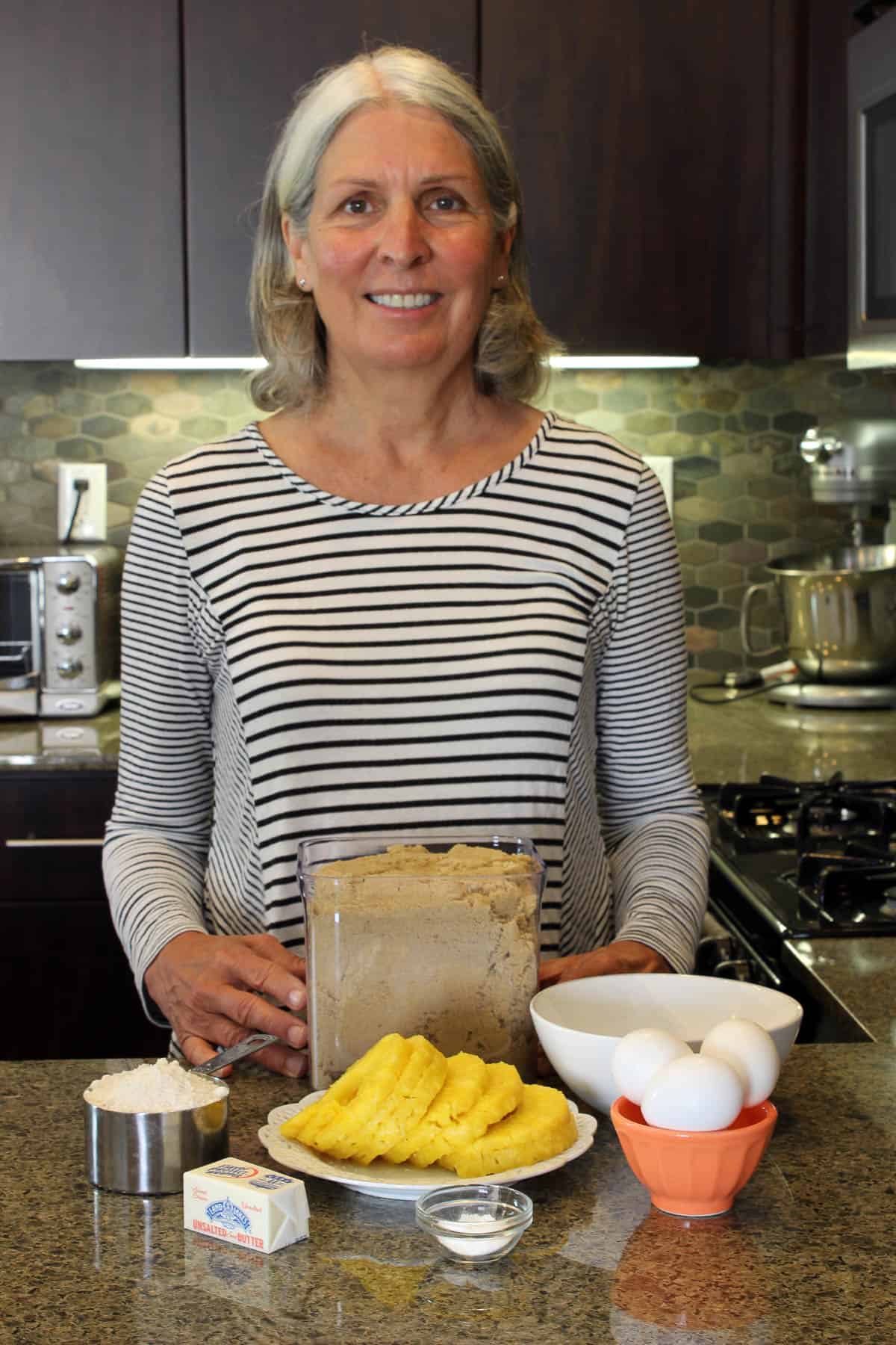 picture of a woman standing next to a counter with pineapple upside down cake ingredients