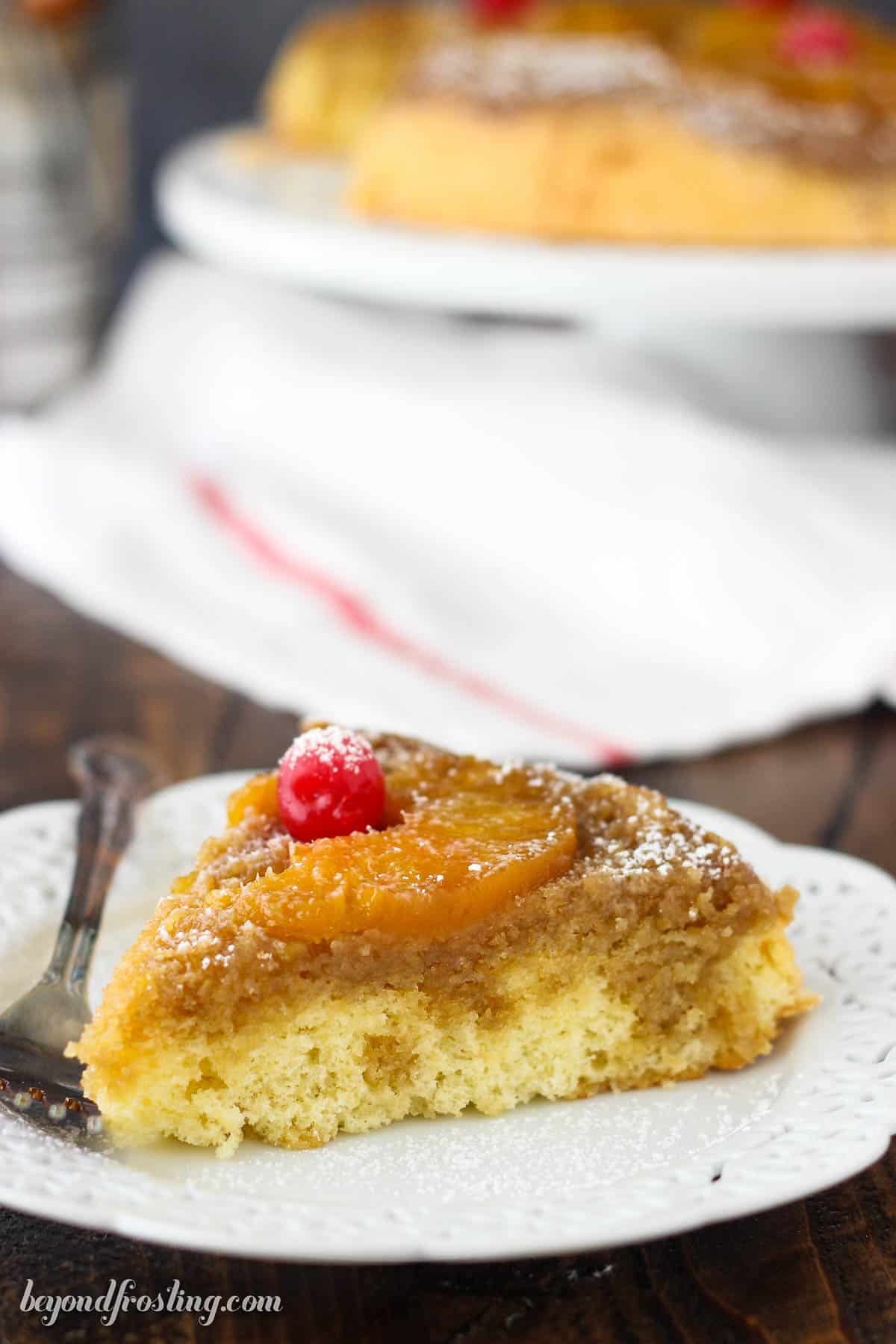 side view of a slice of pineapple cake on a white plate next to a fork