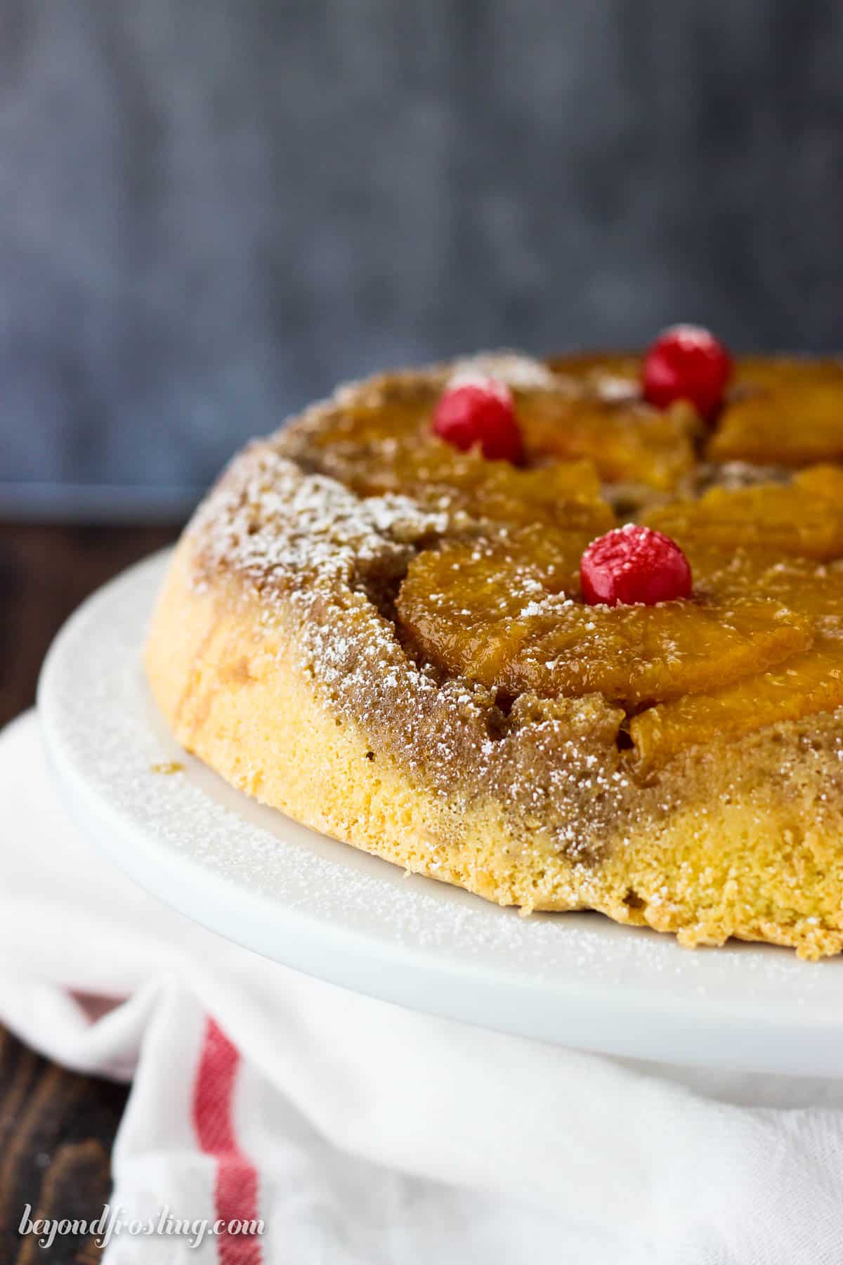 side view of a whole pineapple upside down cake on a cake stand