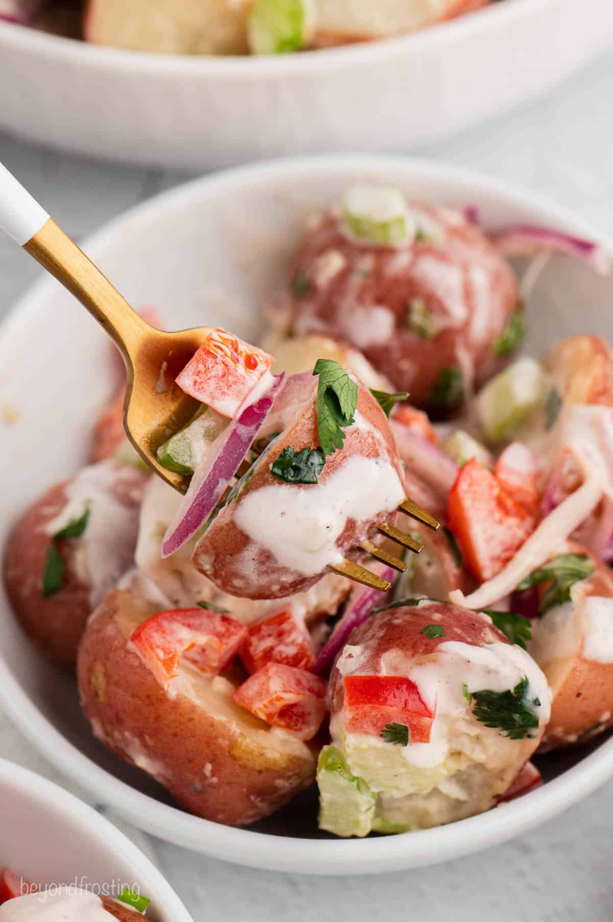 A fork in a bowl of red potato salad