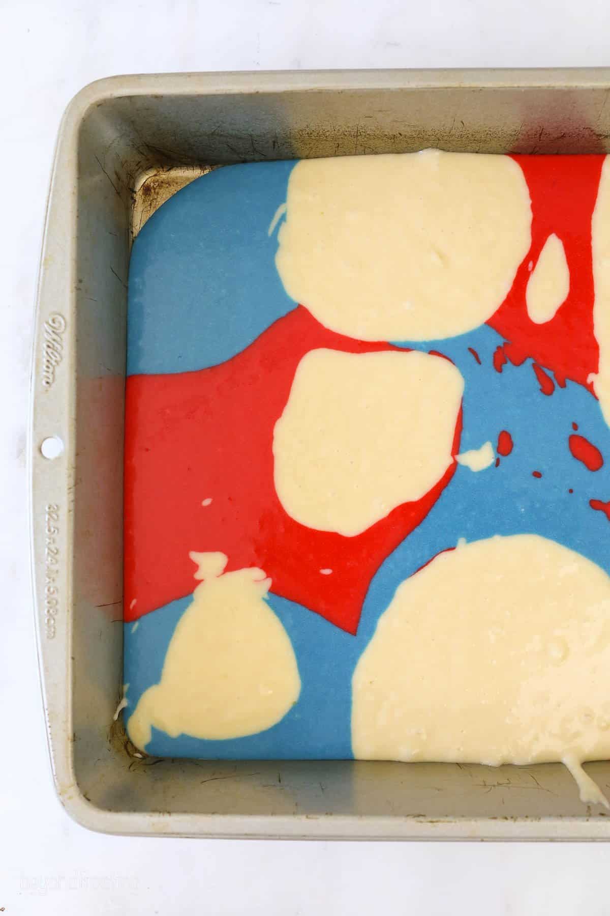 red white and blue cake batter in a cake pan