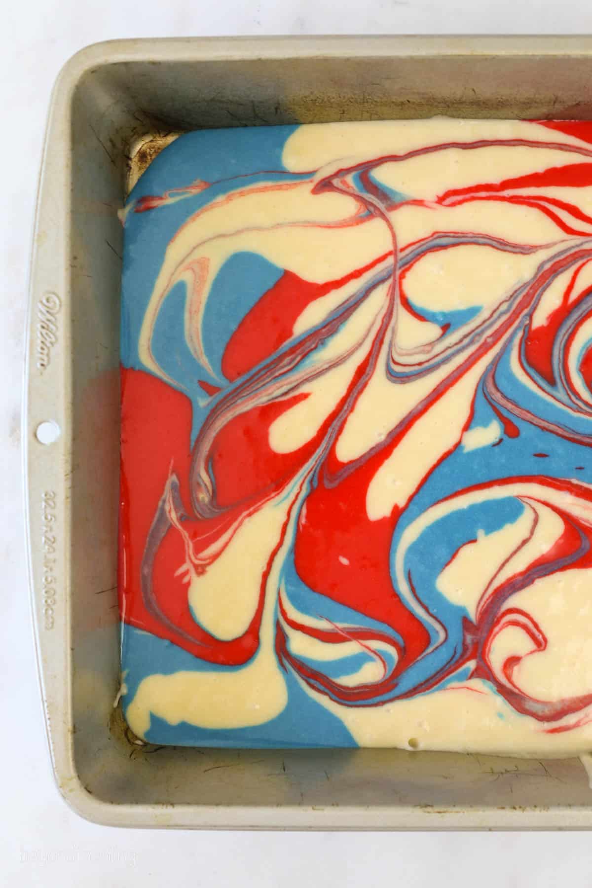 red white and blue cake batter swirled in a cake pan