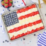 overhead view of an American Flag cake decorated with blueberries, strawberries and whipped cream