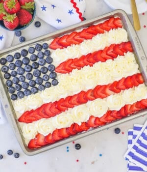 overhead view of an American Flag cake decorated with blueberries, strawberries and whipped cream
