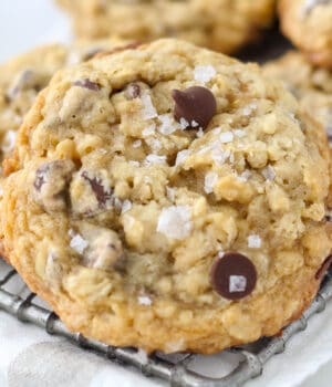 closeup of a salted caramel oatmeal cookie on a cooling rack garnished with flakey sea salt