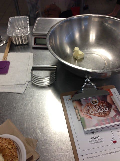 A stainless bowl with a few tablespoons of butter on a work surface with Bake for Good papers