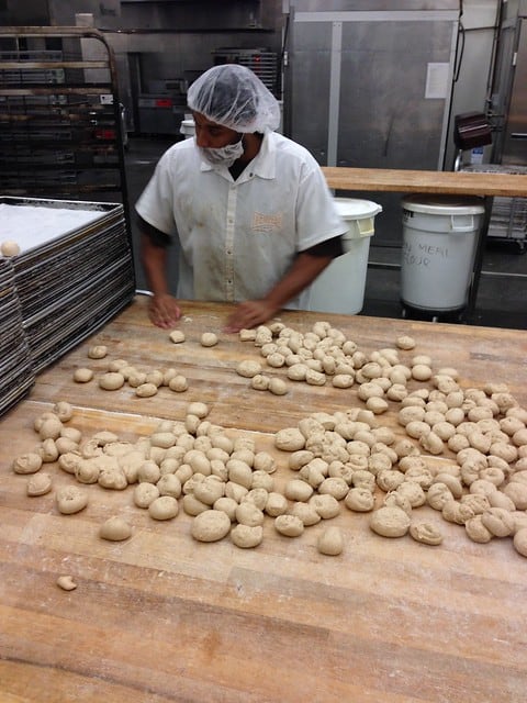A worker at Homeboy restaurant working at a wooden table filled with balls of dough