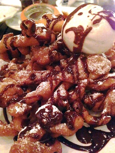 Close-up of funnel cake with vanilla ice cream and chocolate drizzle