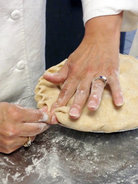 Chef Robyn crimping a pie crust by hand