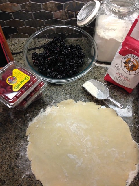 Fresh berries next to a rolled-out pie crust