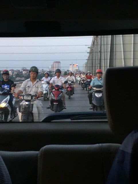 View out the back windshield of a car looking at motorcycle traffic behind