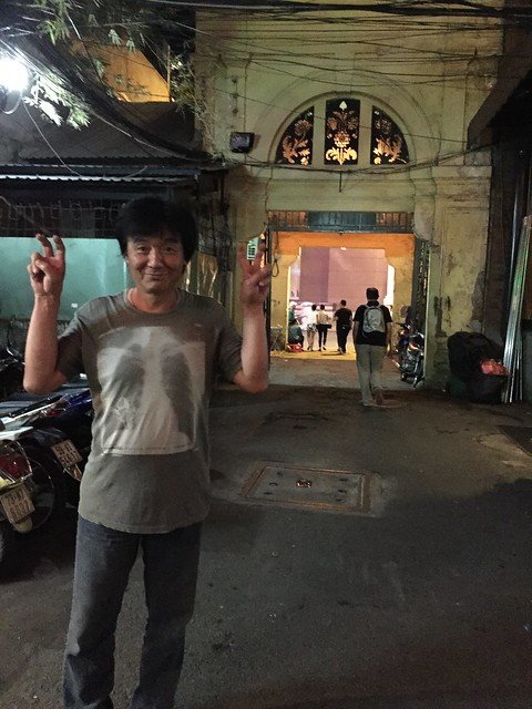 A man posing with two fingers up outside a restaurant