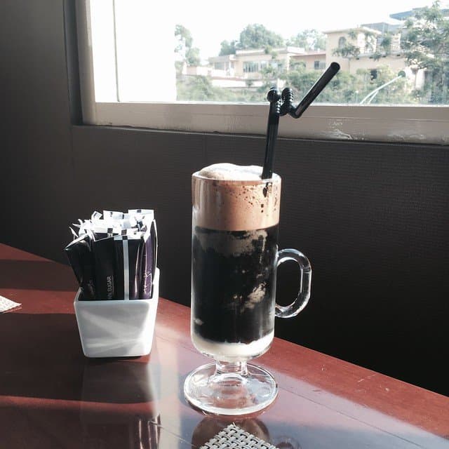 Coffee in a tall clear glass mug with a straw