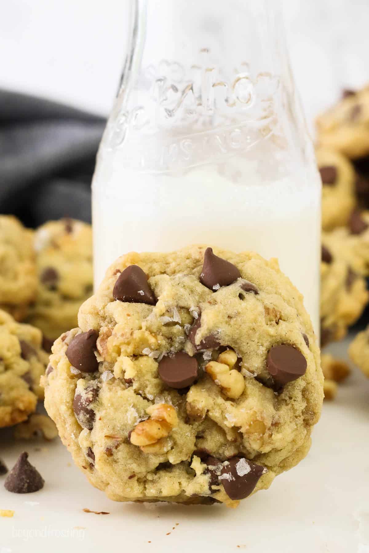 A chocolate chip walnut cookie against a glass of milk