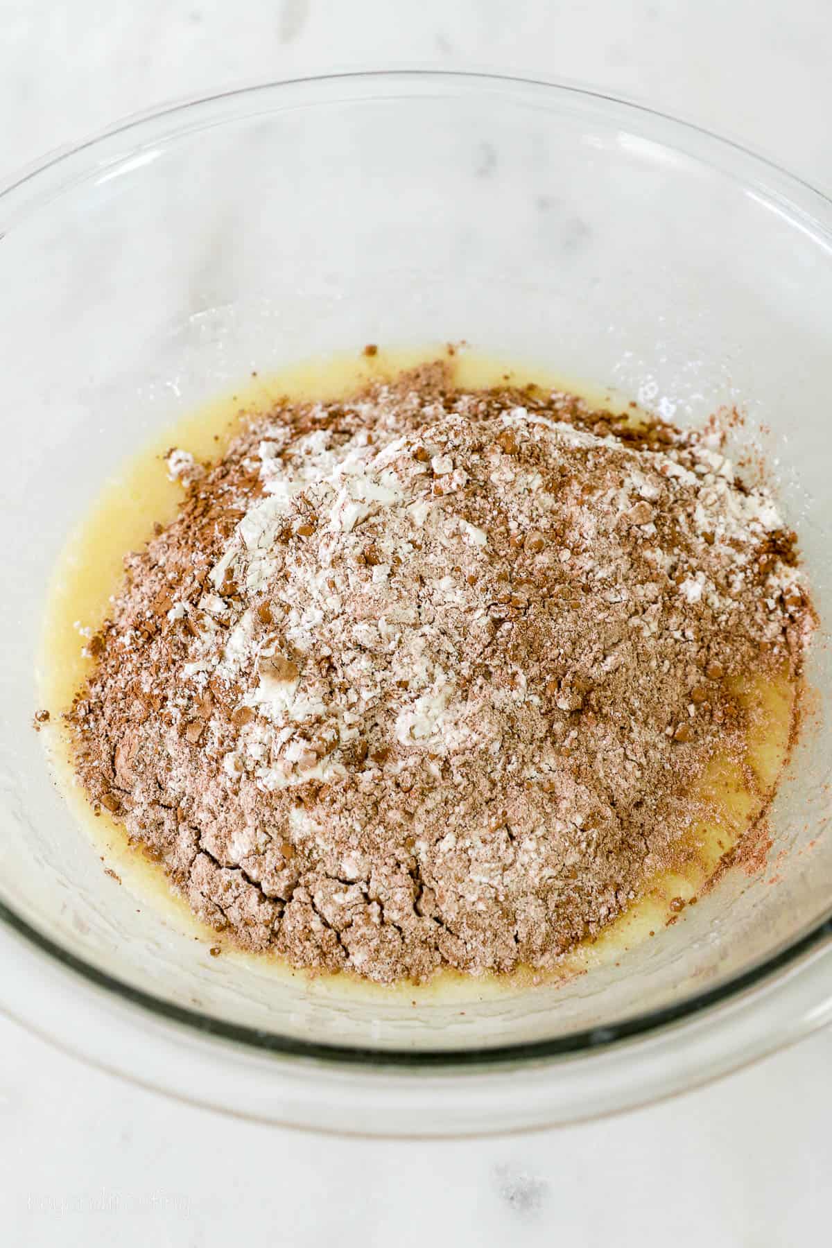 glass mixing bowl with flour, cocoa powder and liquid mixture