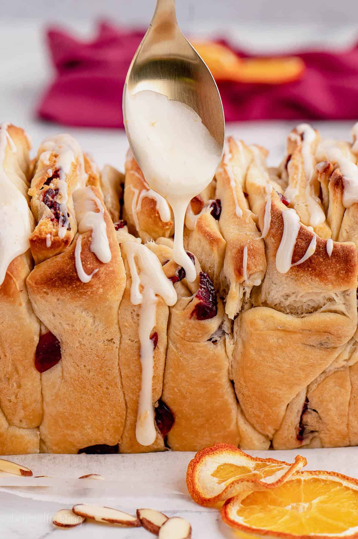 closeup of baked cranberry orange bread being drizzled with icing