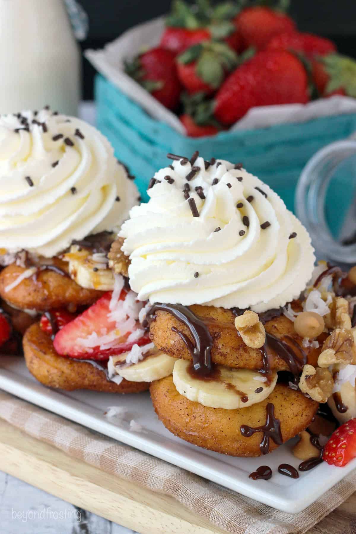 side view of a plate filled with dessert nachos with a container of fresh strawberries in the background