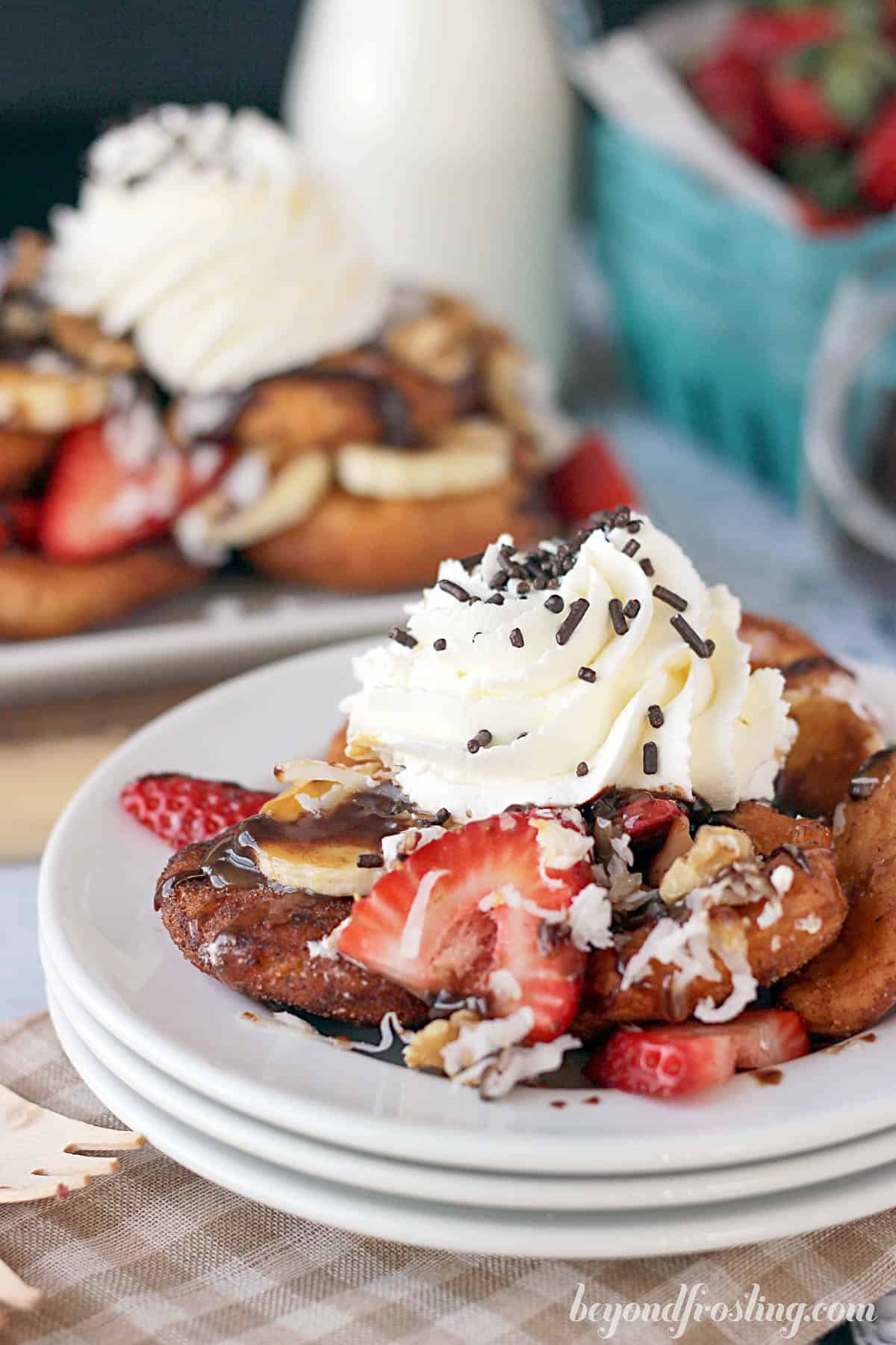 three plates stacked and topped with a pile of dessert nachos topped with fruit and whip