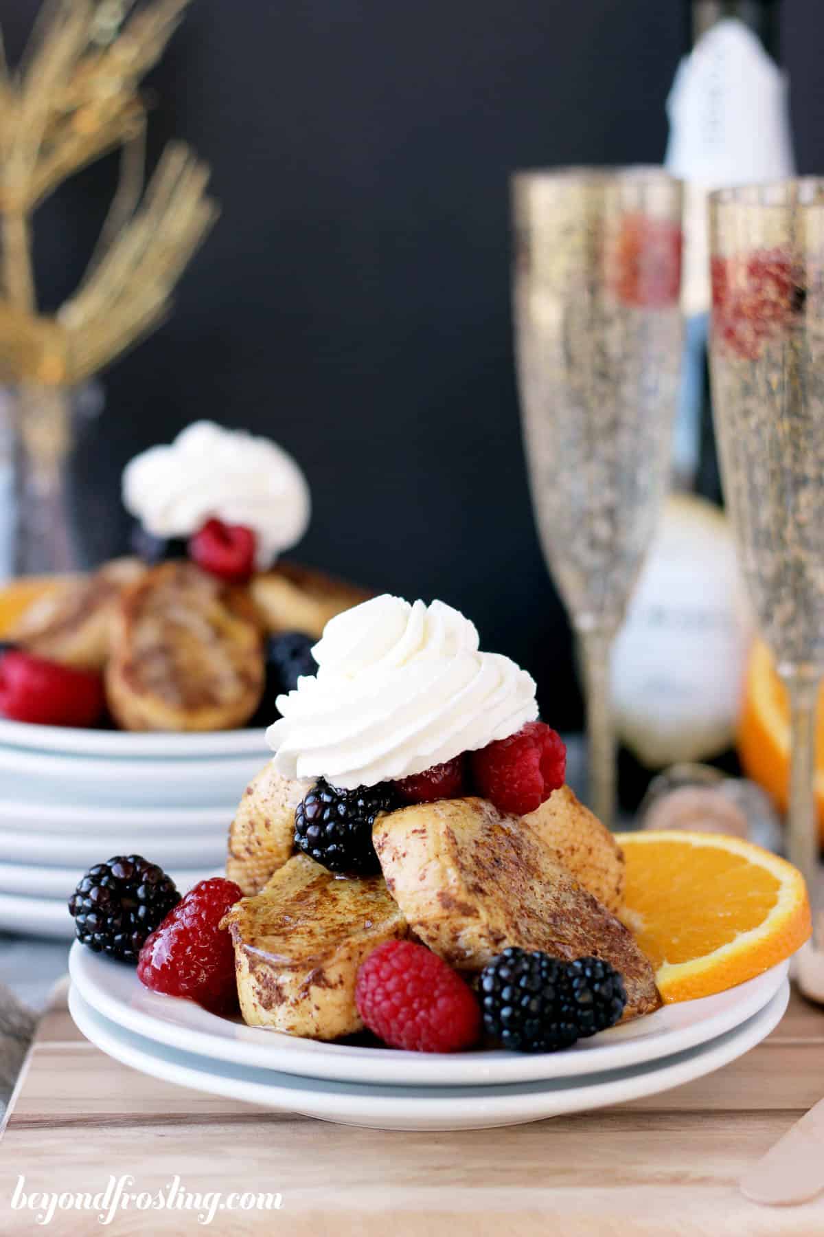 a plate piled with french toast topped with berries and whipped cream