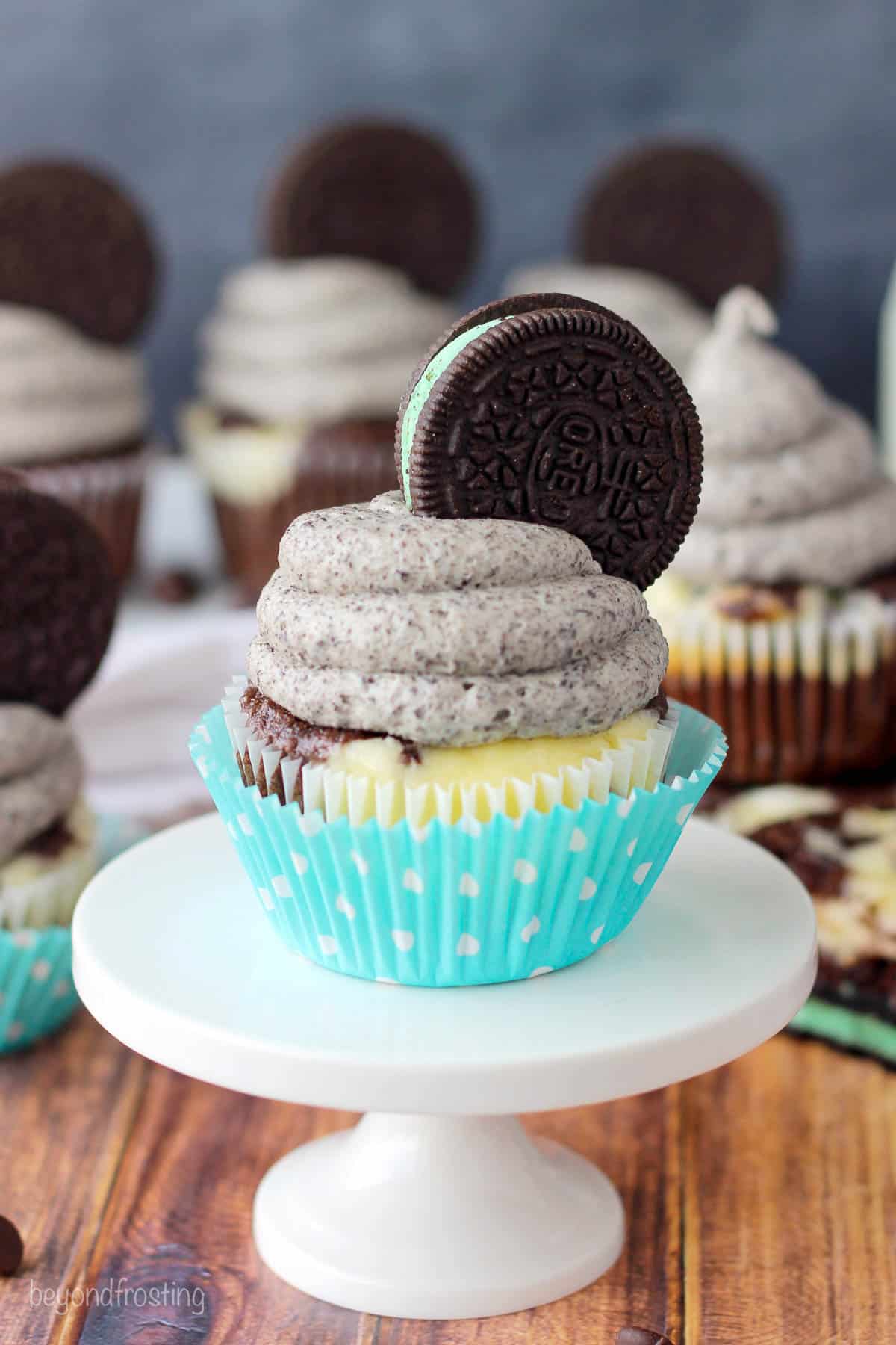 side view of a mint oreo cheesecake cupcake on a small cupcake stand