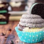 Closeup side view of a cheesecake cupcake topped with frosting and a mint oreo