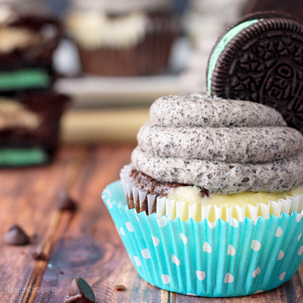 Closeup side view of a cheesecake cupcake topped with frosting and a mint oreo
