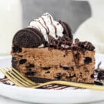 A close up of a slice of Chocolate Oreo Cheesecake with a gold fork