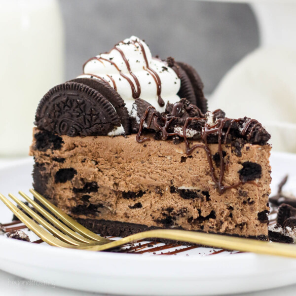 A close up of a slice of Chocolate Oreo Cheesecake with a gold fork