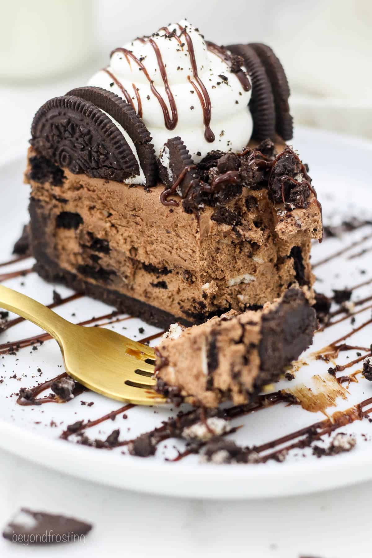 A slice of Oreo Chocolate Cheesecake with a bite missing and a gold fork