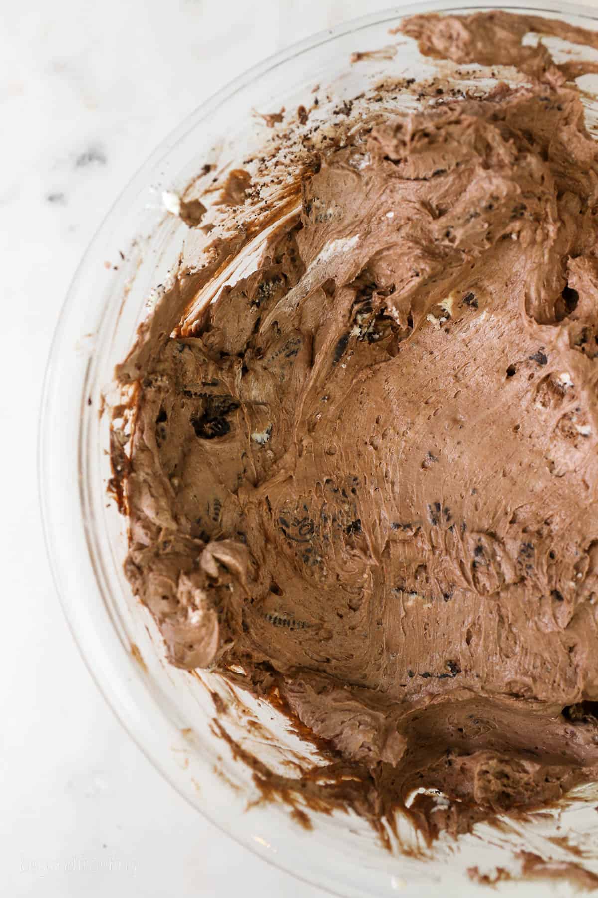 A glass mixing bowl with chocolate cheesecake batter
