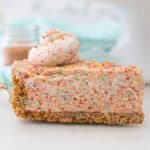 A slice of Fruity Pebble Cheesecake on a pie server