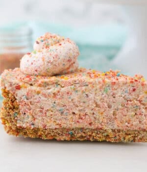 A slice of Fruity Pebble Cheesecake on a pie server
