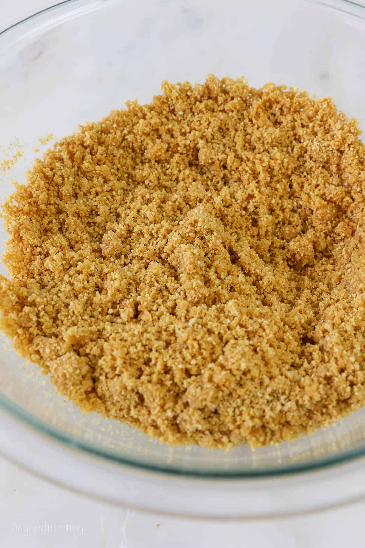 a bowl of graham cracker crumbs mixed with butter