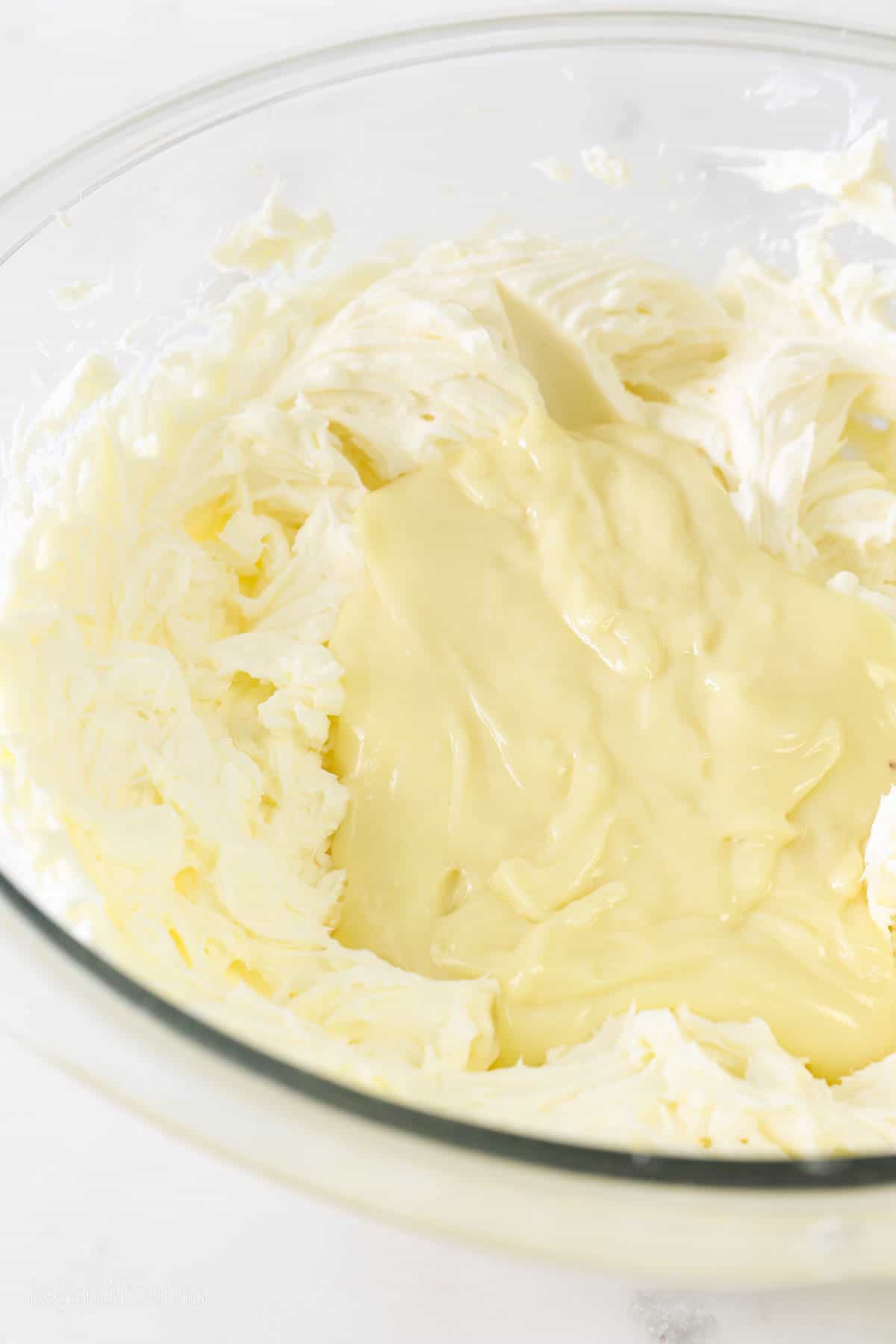 a glass mixing bowl with no-bake cheesecake filling and white chocolate