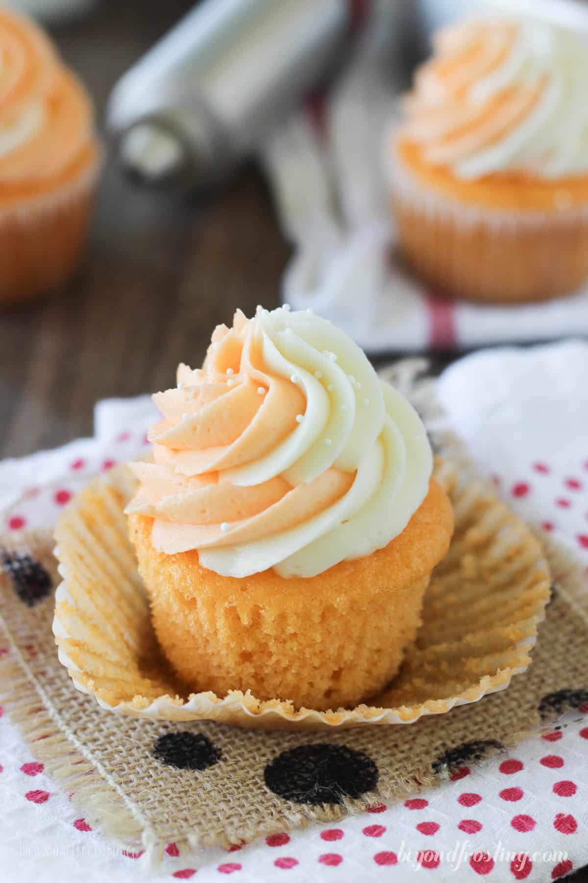 side view overhead of an orange cream pop cupcake with more cupcakes in the background