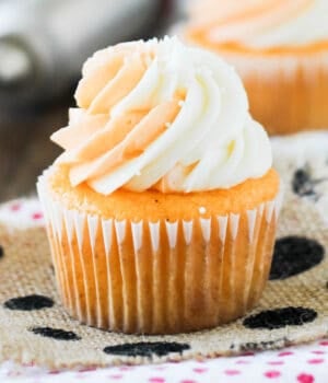 side view closeup of an orange cream cupcake topped with frosting