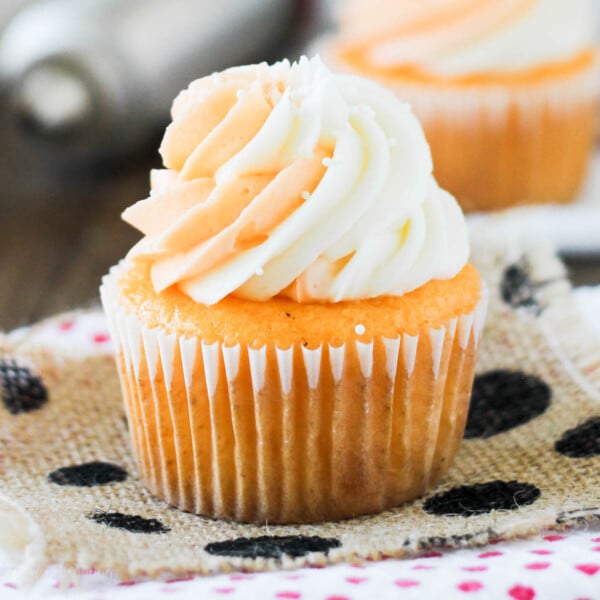 side view closeup of an orange cream cupcake topped with frosting