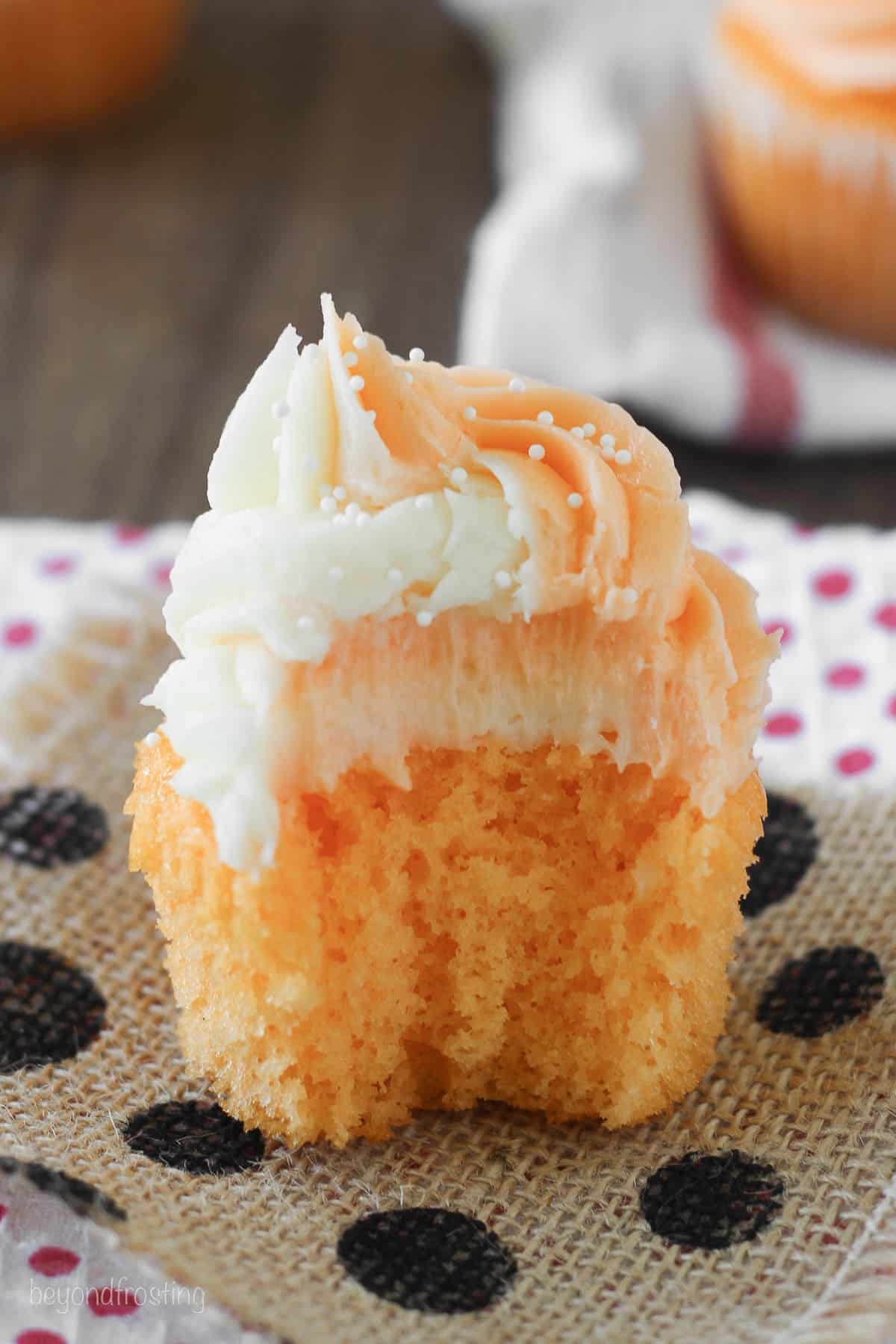 side view of an orange cream cupcake with a bite taken out