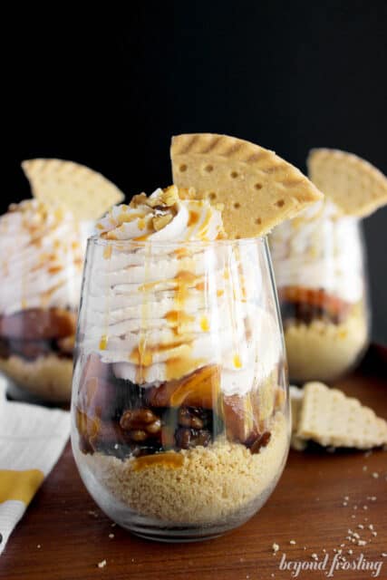 side view of a peach shortbread parfait in a glass with two more parfaits in the background