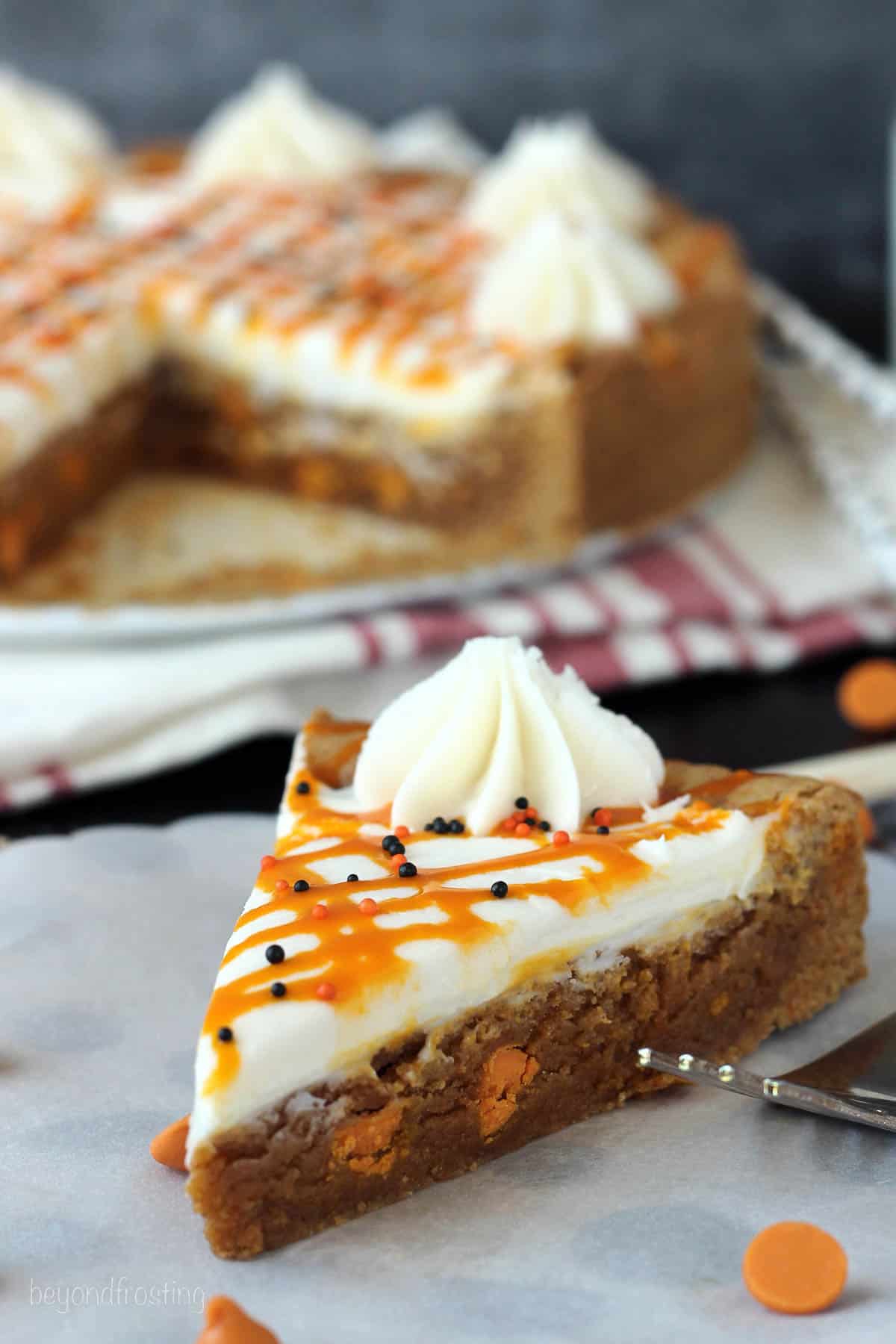 side view of a slice of pumpkin cookie cake with a whole cookie cake in the background